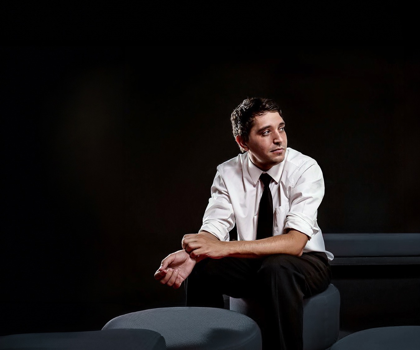 Mark Shaun Hopkins sitting thoughtfully in a modern office space with a whiteboard full of creative and complex diagrams.