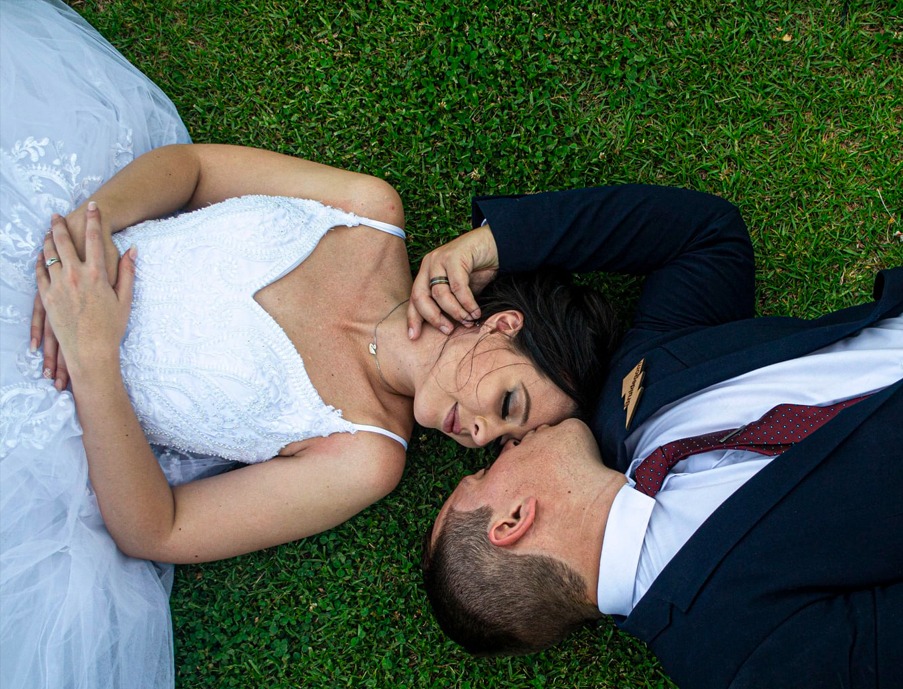 Wedding photo of a bride and groom lying on the grass, photographed by Mark Shaun Hopkins.